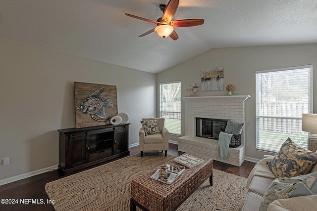 living room with ceiling fan, a fireplace, dark hardwood / wood-style flooring, and vaulted ceiling