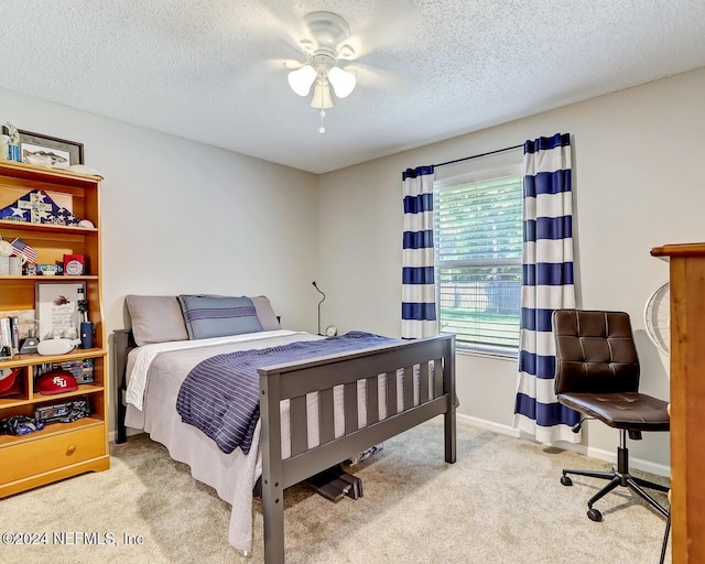 bedroom with ceiling fan, light colored carpet, and a textured ceiling