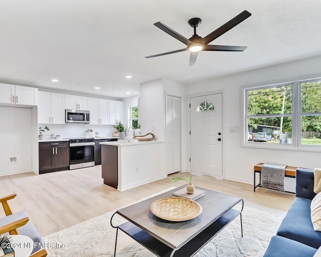 living room featuring ceiling fan, plenty of natural light, sink, and light hardwood / wood-style floors