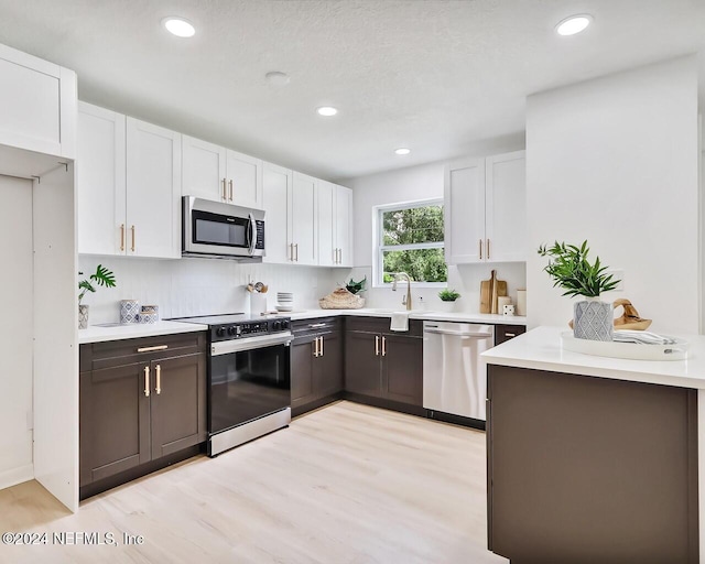 kitchen with white cabinetry, light wood-type flooring, and appliances with stainless steel finishes