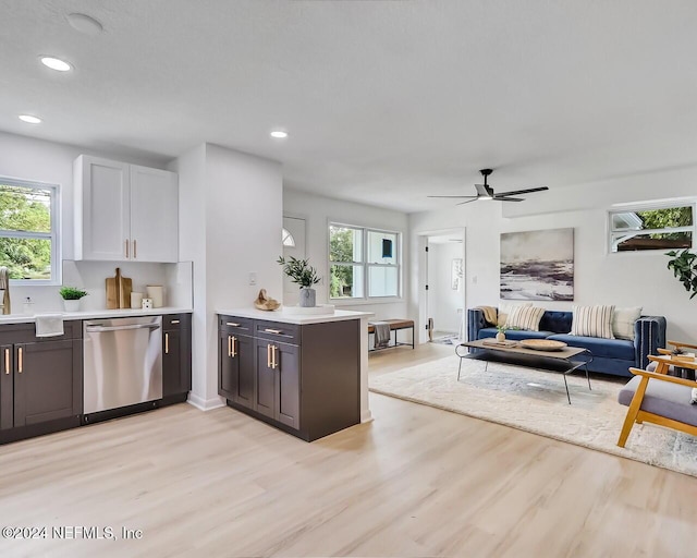 kitchen featuring white cabinetry, stainless steel dishwasher, a healthy amount of sunlight, and light wood-type flooring