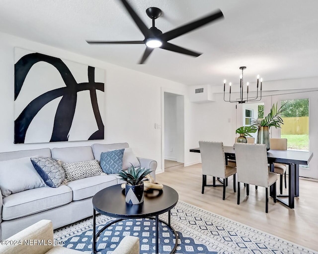 living room with ceiling fan with notable chandelier and light wood-type flooring