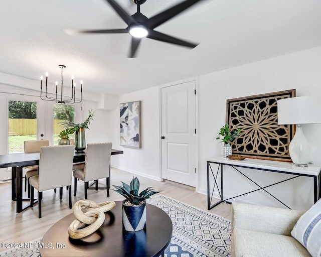 living room featuring french doors, ceiling fan with notable chandelier, and light hardwood / wood-style flooring