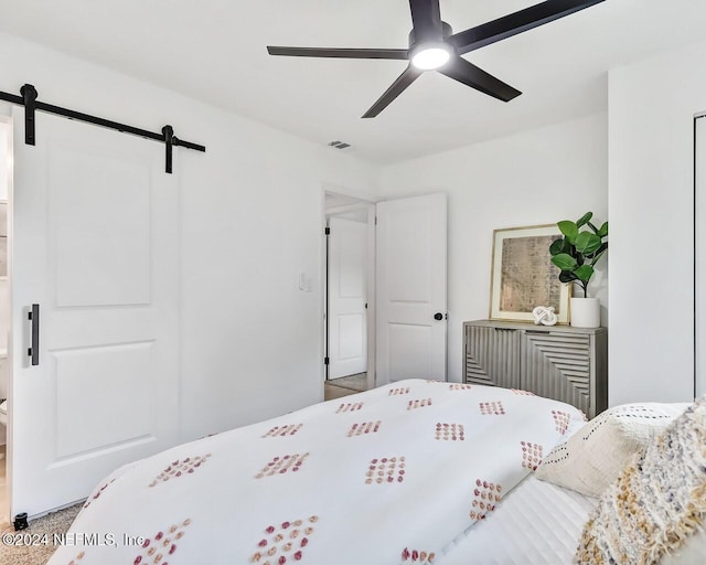 bedroom with a barn door and ceiling fan