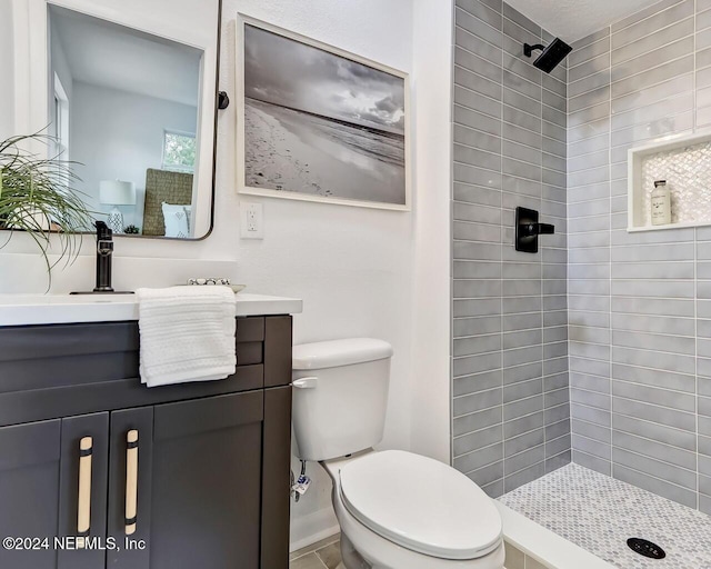 bathroom with tiled shower, vanity, and toilet