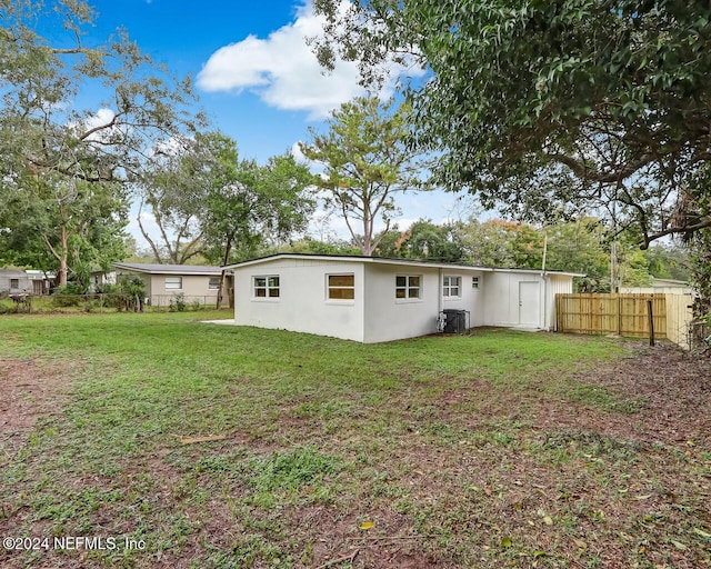 back of property featuring a lawn and central air condition unit