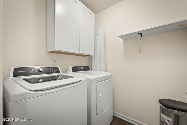 clothes washing area featuring dark wood-type flooring, cabinets, washer and dryer, and a textured ceiling