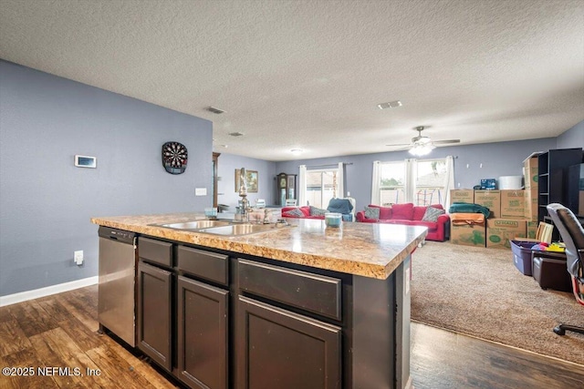 kitchen featuring sink, dark hardwood / wood-style flooring, stainless steel dishwasher, a center island with sink, and a textured ceiling