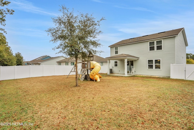 back of property with a lawn and a playground