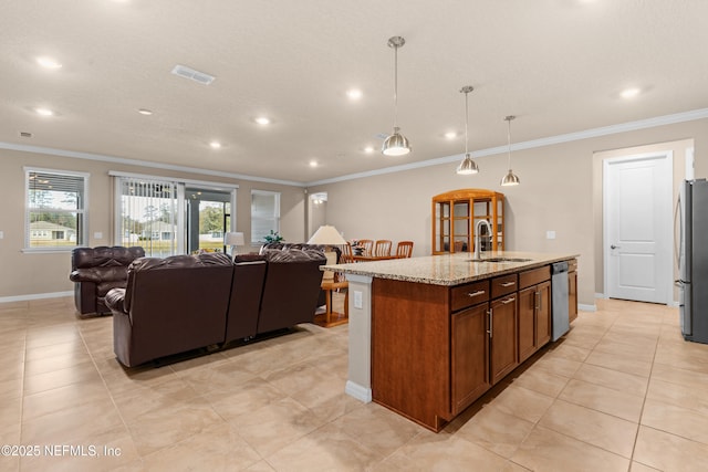 kitchen with sink, light stone counters, pendant lighting, stainless steel appliances, and a kitchen island with sink