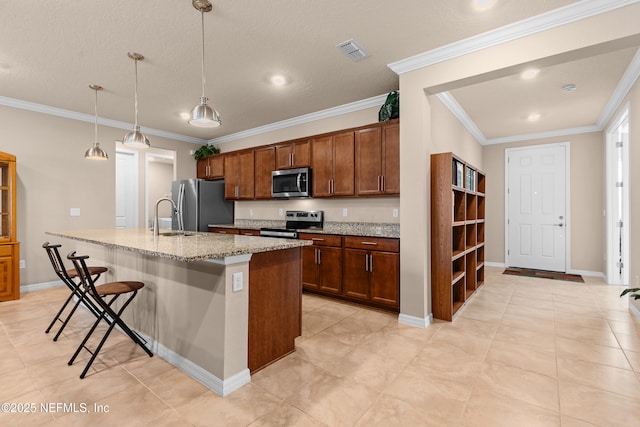 kitchen featuring light stone counters, a kitchen breakfast bar, an island with sink, pendant lighting, and stainless steel appliances