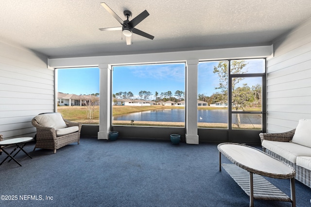 sunroom / solarium featuring ceiling fan and a water view