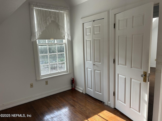 unfurnished bedroom with dark hardwood / wood-style flooring, vaulted ceiling, and a closet