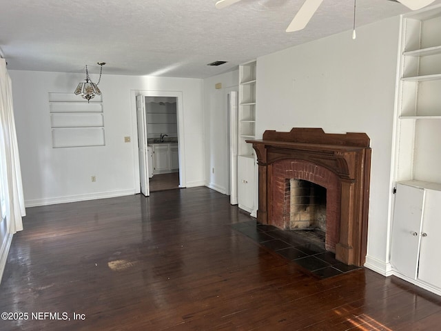 unfurnished living room featuring a textured ceiling, dark hardwood / wood-style floors, built in features, ceiling fan, and a fireplace