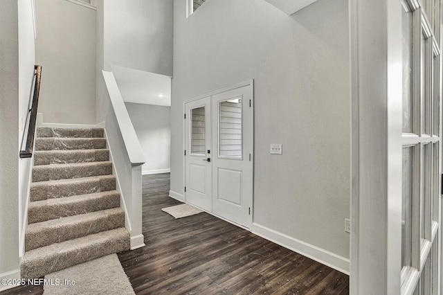 stairway with hardwood / wood-style floors and a towering ceiling