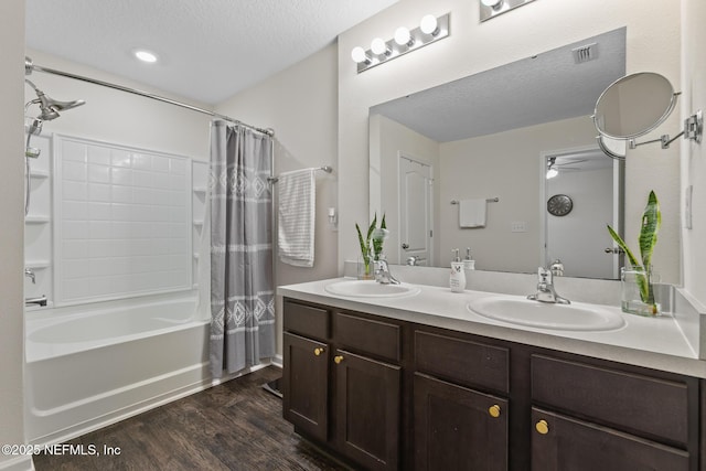 bathroom featuring hardwood / wood-style flooring, vanity, shower / tub combo, and a textured ceiling