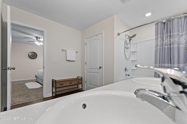 bathroom with ceiling fan, double sink,  shower combination, and a textured ceiling