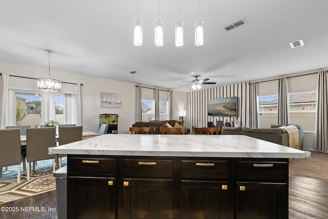 kitchen featuring a kitchen island, ceiling fan with notable chandelier, decorative light fixtures, dark hardwood / wood-style flooring, and a textured ceiling