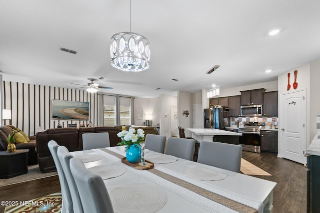 dining space with ceiling fan with notable chandelier and dark wood-type flooring