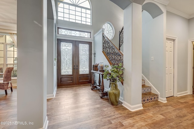 entrance foyer featuring a high ceiling, light hardwood / wood-style floors, and french doors