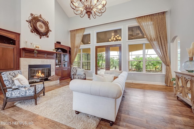 living room with hardwood / wood-style flooring, a fireplace, high vaulted ceiling, and french doors