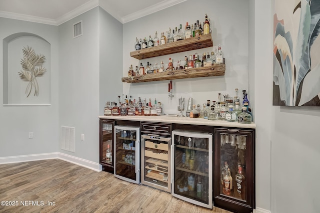 bar featuring wine cooler, crown molding, and light hardwood / wood-style flooring