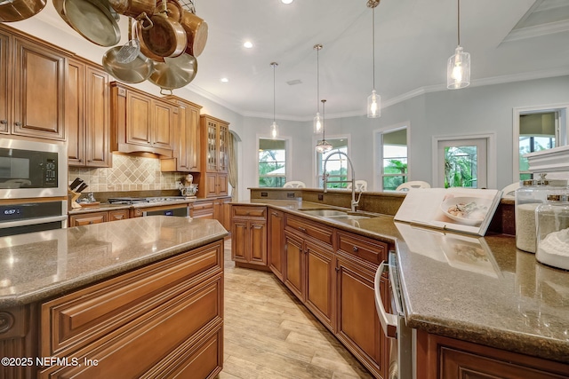 kitchen with a large island, sink, pendant lighting, stainless steel appliances, and tasteful backsplash