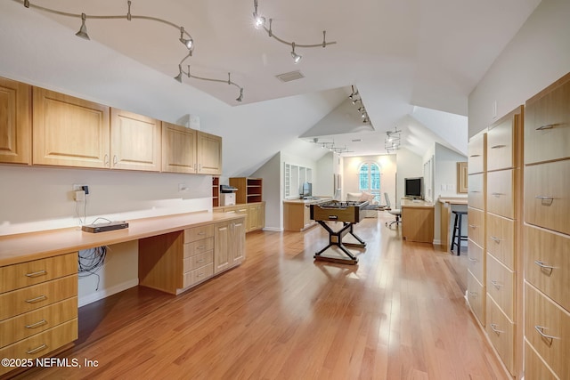 kitchen featuring vaulted ceiling, built in desk, light brown cabinetry, track lighting, and light wood-type flooring