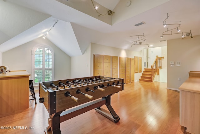 rec room featuring rail lighting, lofted ceiling, and light hardwood / wood-style floors