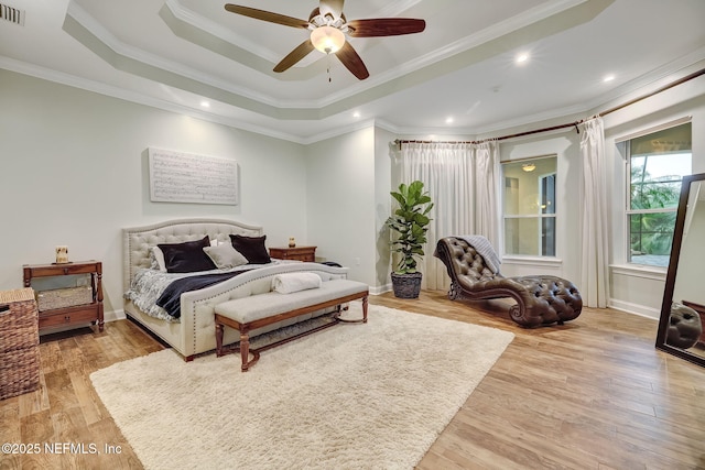 bedroom with ornamental molding, a raised ceiling, and light wood-type flooring