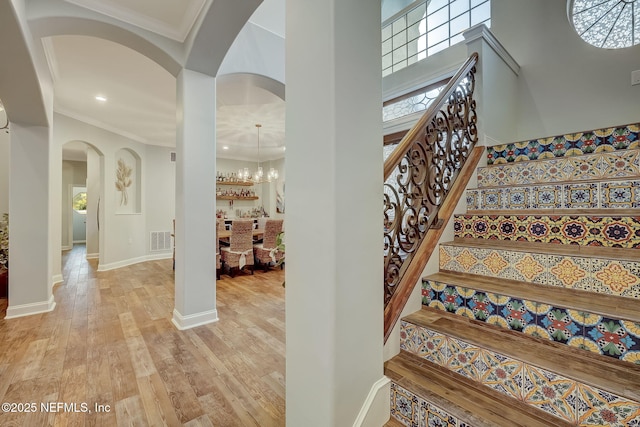 stairs with crown molding, a towering ceiling, and hardwood / wood-style floors