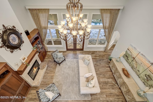 living room with a notable chandelier, a high end fireplace, hardwood / wood-style floors, and french doors