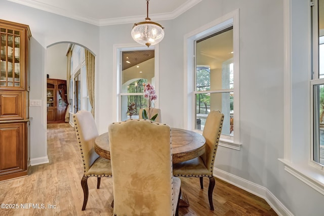 dining space with a notable chandelier, ornamental molding, and light hardwood / wood-style floors