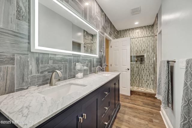 bathroom with hardwood / wood-style flooring, vanity, tile walls, and backsplash