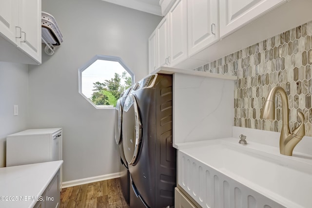 laundry room featuring dark hardwood / wood-style flooring, sink, washer and clothes dryer, and cabinets