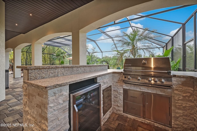 view of patio with grilling area, beverage cooler, glass enclosure, and exterior kitchen