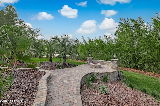 view of home's community with a lawn, a patio, and an outdoor fire pit