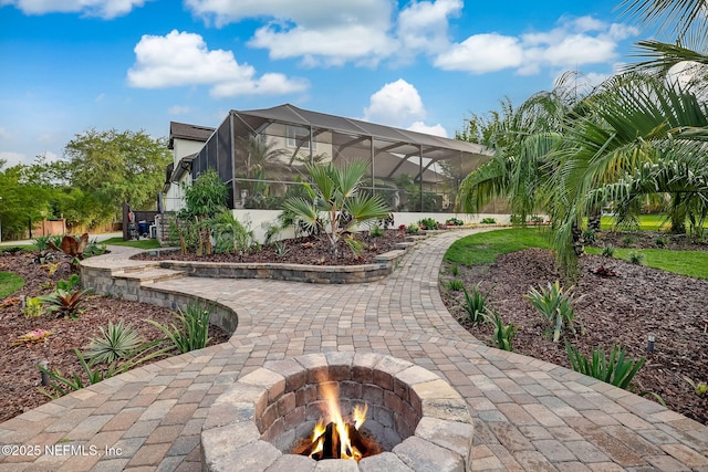 view of patio featuring glass enclosure and a fire pit