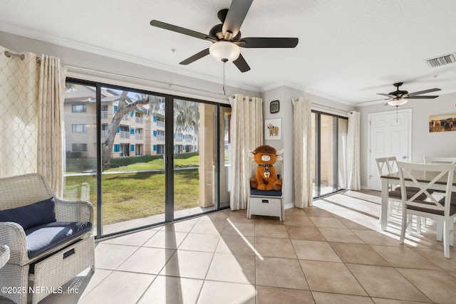 interior space featuring ornamental molding, a healthy amount of sunlight, a textured ceiling, and ceiling fan