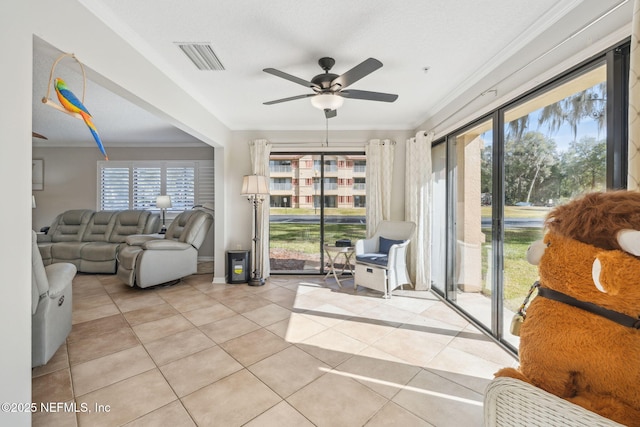 tiled living room featuring ceiling fan, ornamental molding, and a textured ceiling