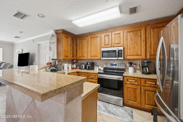 kitchen with light tile patterned floors, appliances with stainless steel finishes, ornamental molding, a textured ceiling, and kitchen peninsula