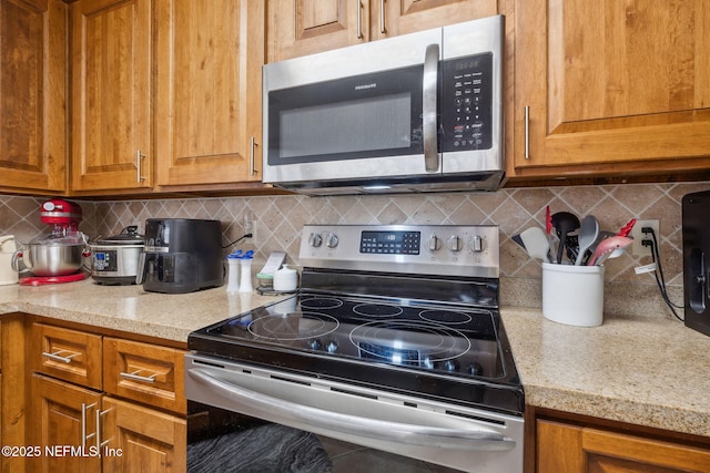 kitchen featuring stainless steel appliances, light stone counters, and decorative backsplash