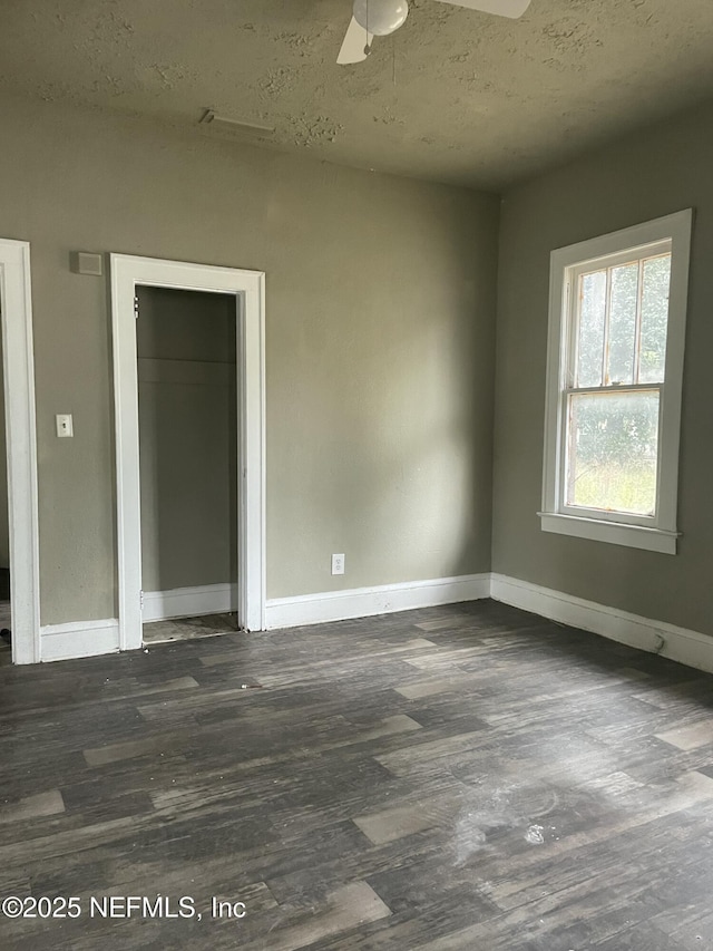 unfurnished room with ceiling fan, a textured ceiling, and dark hardwood / wood-style flooring