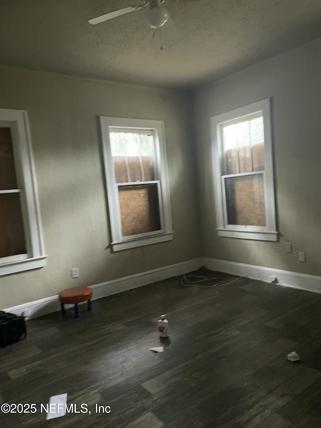 unfurnished room featuring dark wood-type flooring and ceiling fan