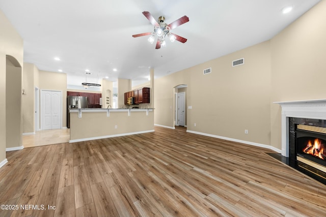 unfurnished living room featuring ceiling fan, a high end fireplace, and light hardwood / wood-style flooring