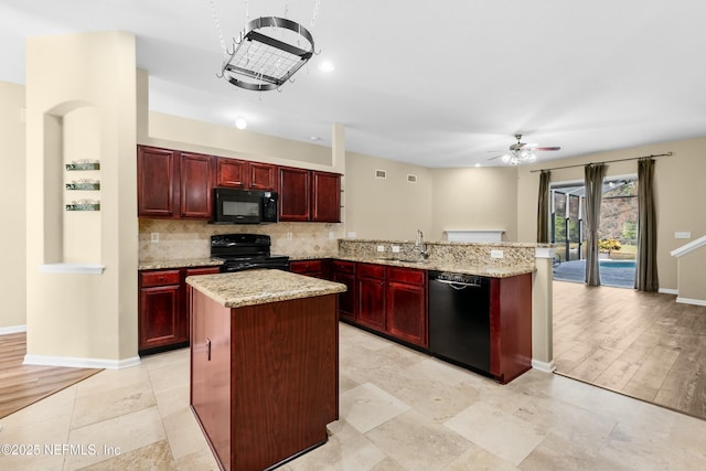 kitchen featuring light stone counters, black appliances, a center island, kitchen peninsula, and backsplash