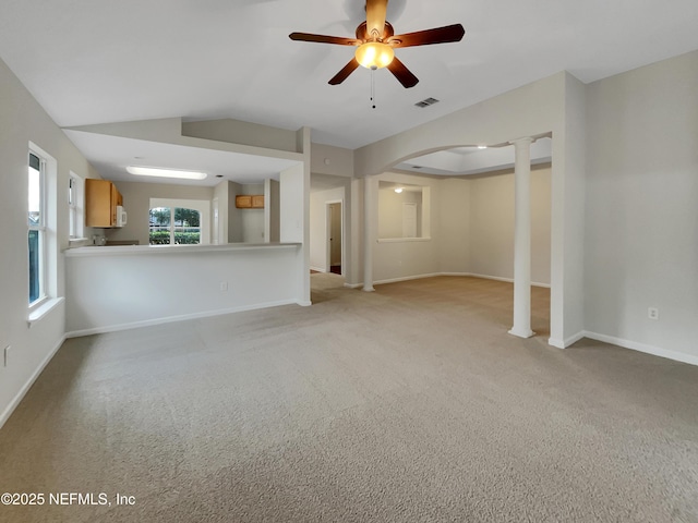 unfurnished living room with vaulted ceiling, light colored carpet, decorative columns, and ceiling fan