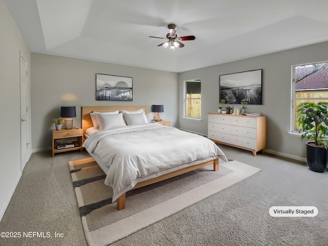 carpeted bedroom featuring a tray ceiling and ceiling fan