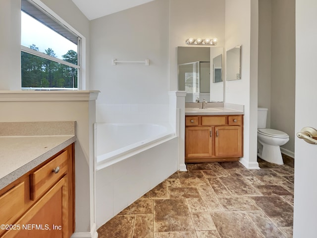 bathroom featuring vanity, tiled bath, and toilet