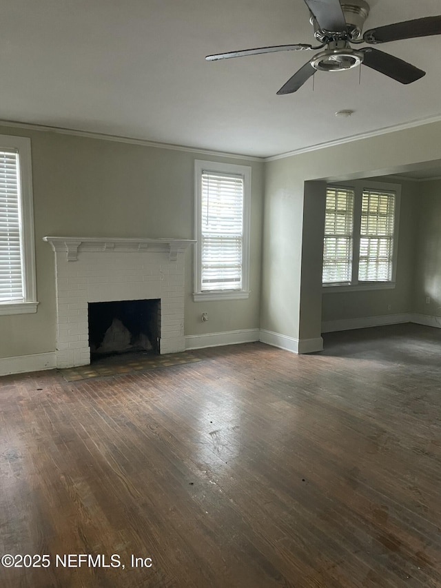 unfurnished living room featuring crown molding, a brick fireplace, dark wood-type flooring, and ceiling fan